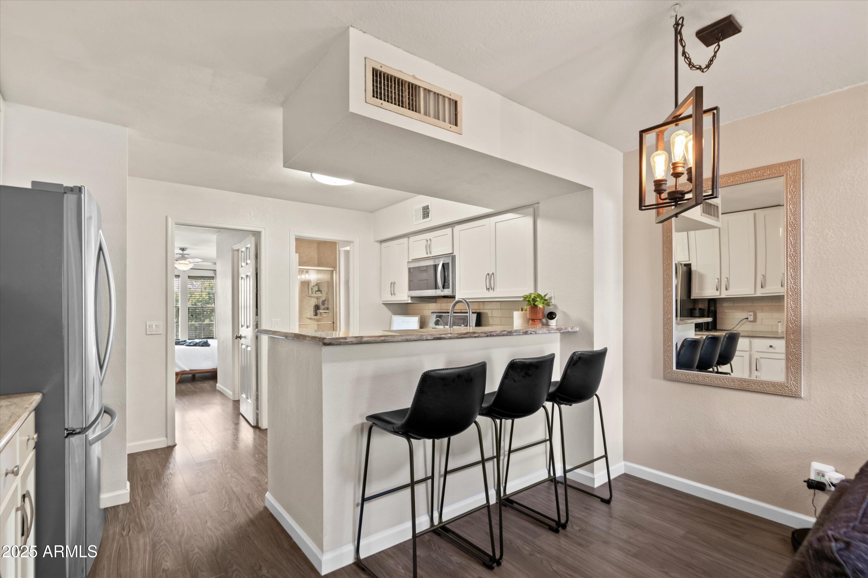 2333 East Southern Avenue, Unit 2067 Tempe, AZ 85282 - Photo 3 of 32 a kitchen with stainless steel appliances a dining table chairs and wooden floor