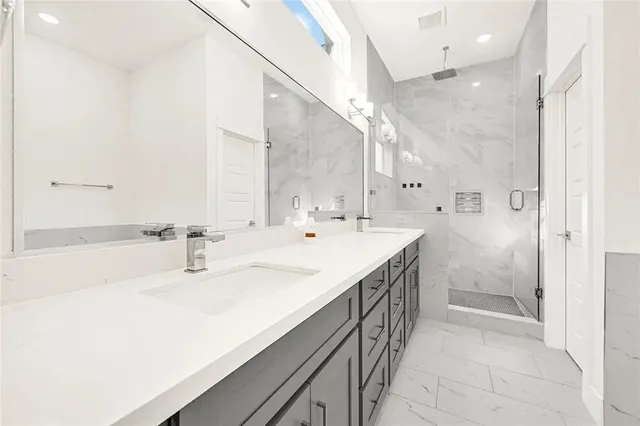 a spacious bathroom with a double vanity sink mirror and shower