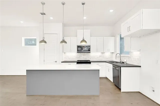 a large kitchen with stainless steel appliances kitchen island granite countertop a sink a stove and a refrigerator