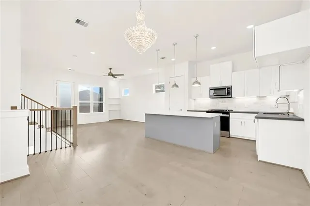a large kitchen with stainless steel appliances kitchen island granite countertop a large counter top and white cabinets