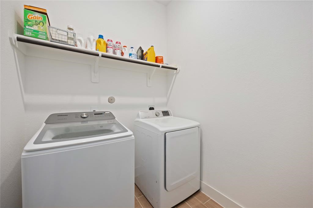 10014 Nectar Path Iowa Colony, TX 77583 - Photo 12 of 26 This photo shows a compact laundry room with a modern washer and dryer, a shelf above for storage, and clean, white walls.