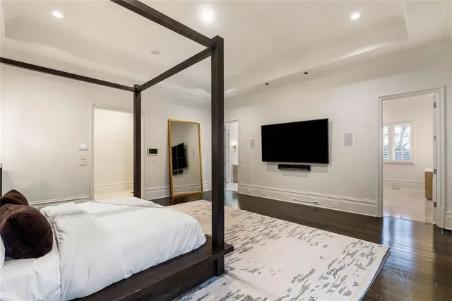 a spacious bedroom with a bed painting on wall and a large window