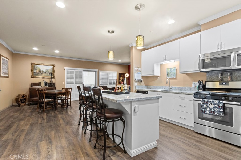 431 South Anaheim Way, Unit 5 Orange, CA 92868 - Photo 8 of 35 a kitchen with stainless steel appliances a dining table chairs stove and white cabinets