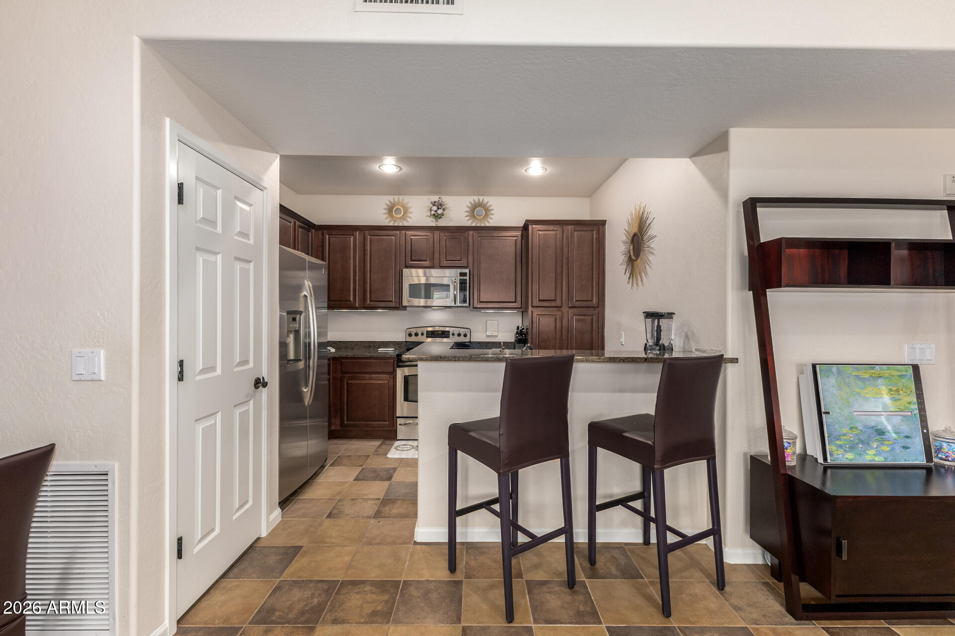 3935 East Rough Rider Road, Unit 1197 Phoenix, AZ 85050 - Photo 14 of 51 a kitchen with stainless steel appliances kitchen island granite countertop a refrigerator and a stove top oven