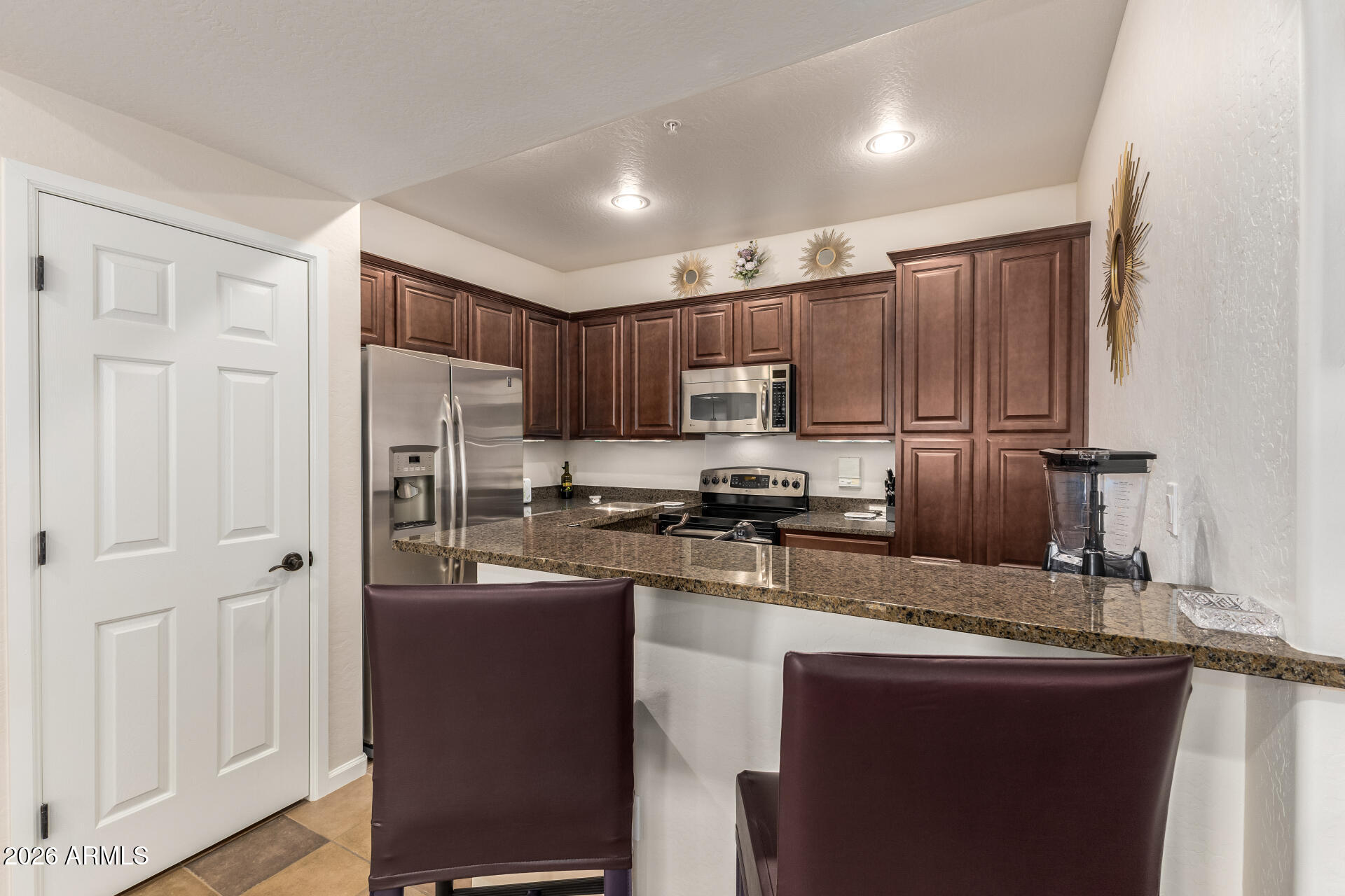 3935 East Rough Rider Road, Unit 1197 Phoenix, AZ 85050 - Photo 16 of 51 a kitchen with kitchen island granite countertop wooden cabinets and refrigerator