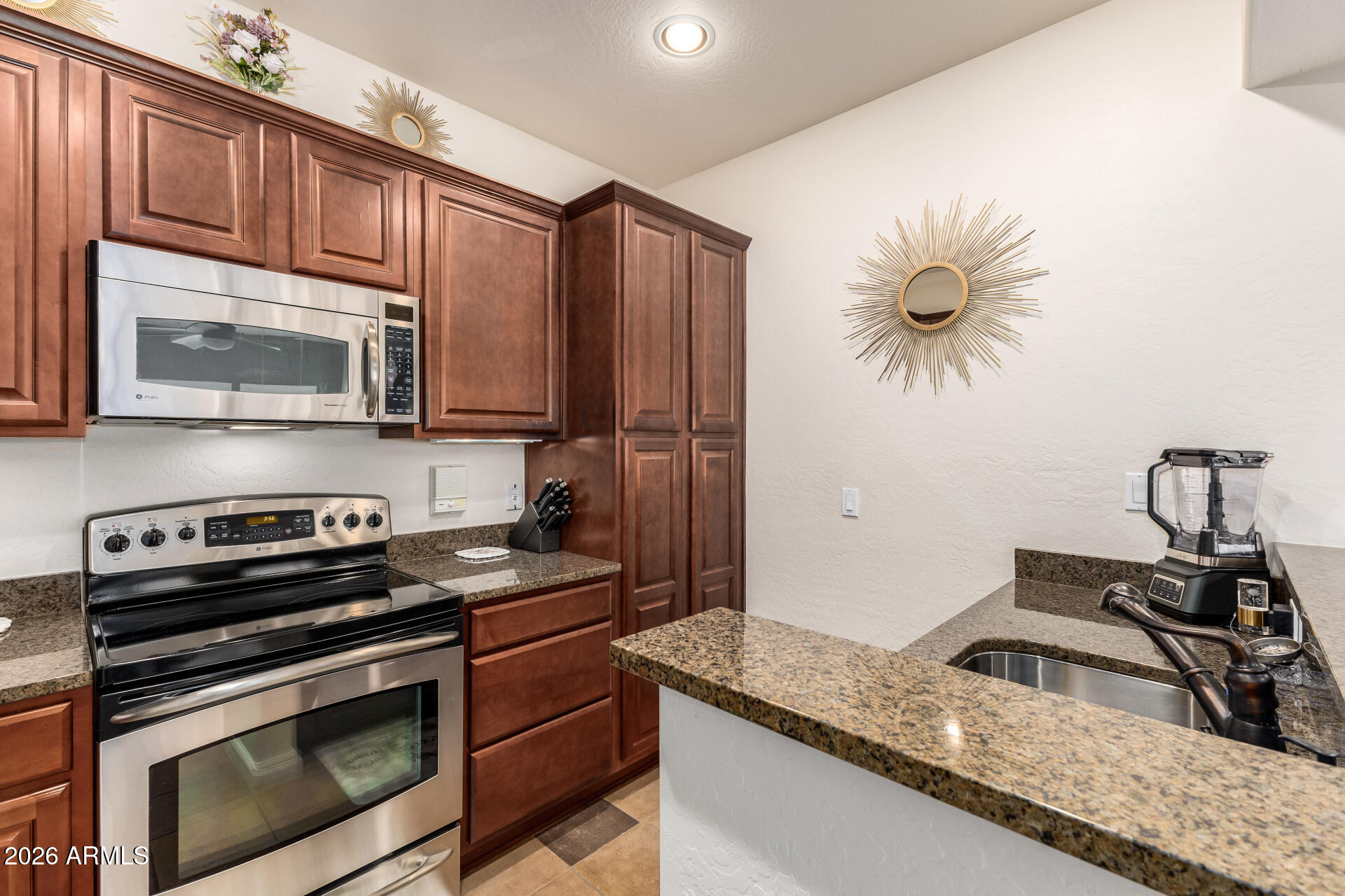 3935 East Rough Rider Road, Unit 1197 Phoenix, AZ 85050 - Photo 17 of 51 a kitchen with stainless steel appliances granite countertop a sink stove and microwave