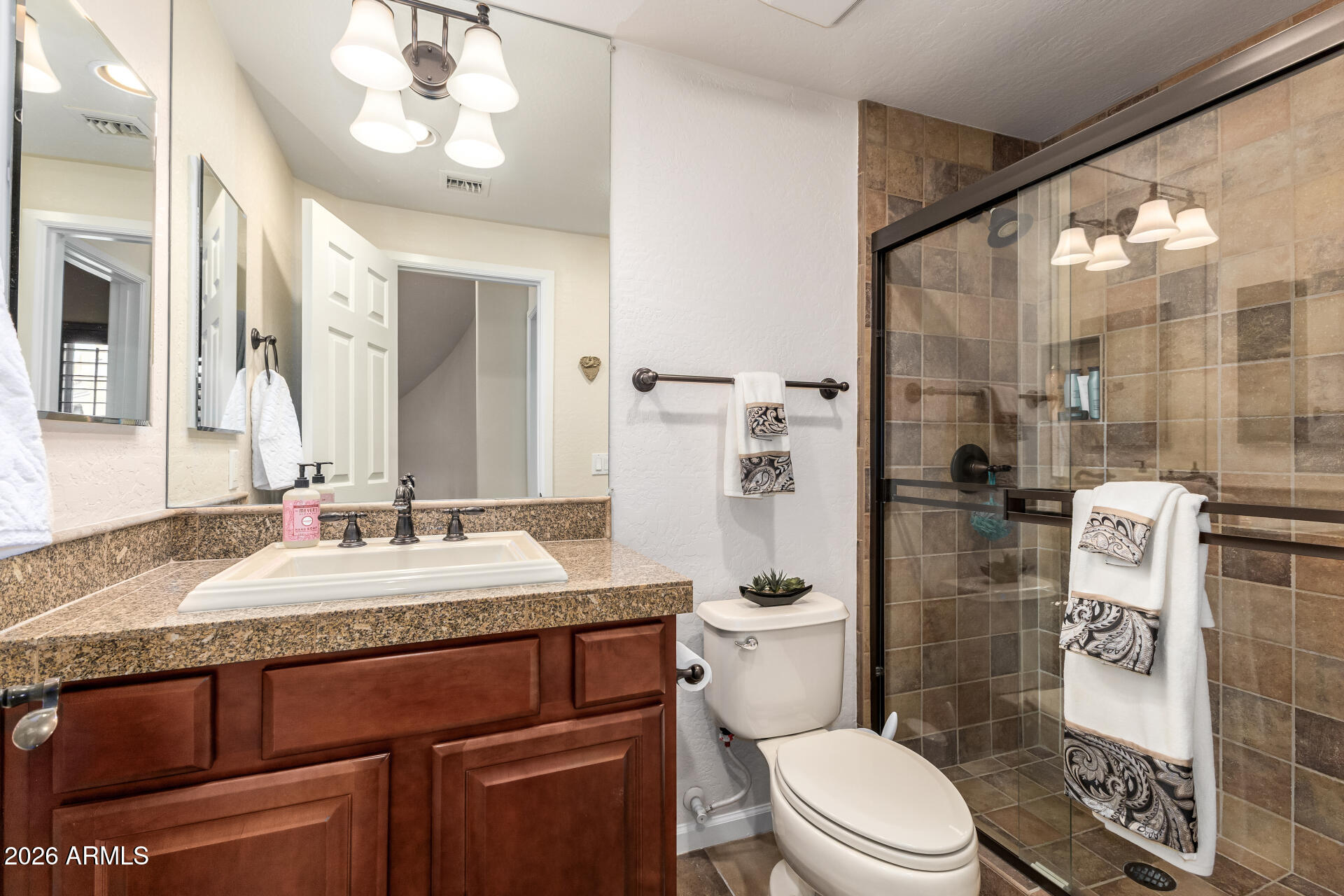 3935 East Rough Rider Road, Unit 1197 Phoenix, AZ 85050 - Photo 24 of 51 a bathroom with a granite countertop sink a toilet a mirror a vanity and shower