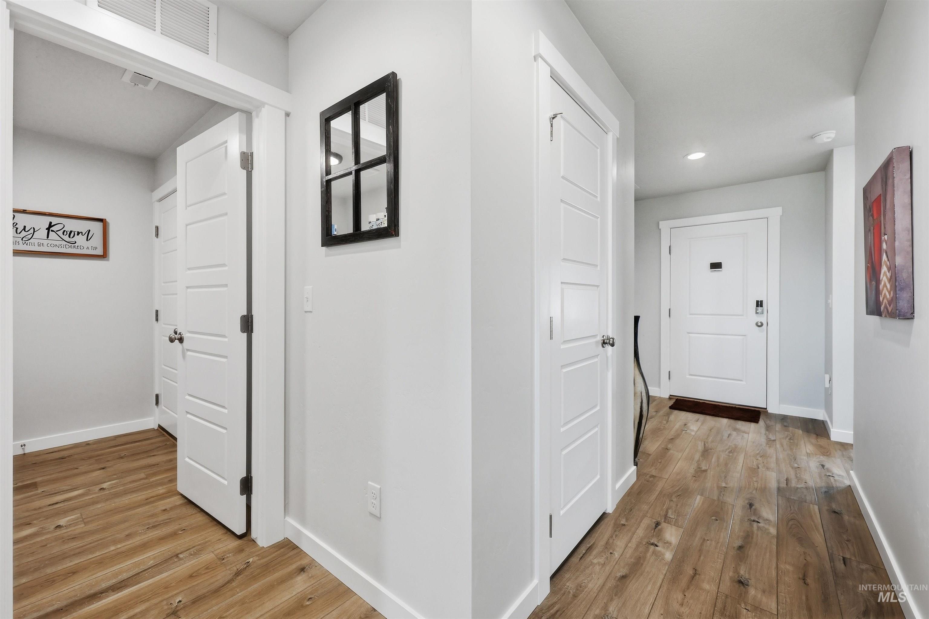 3811 West Maypearl Street Meridian, ID 83642 - Photo 11 of 39 Hallway featuring wood-finish flooring, white paneled doors, white trim, and light gray wall paint