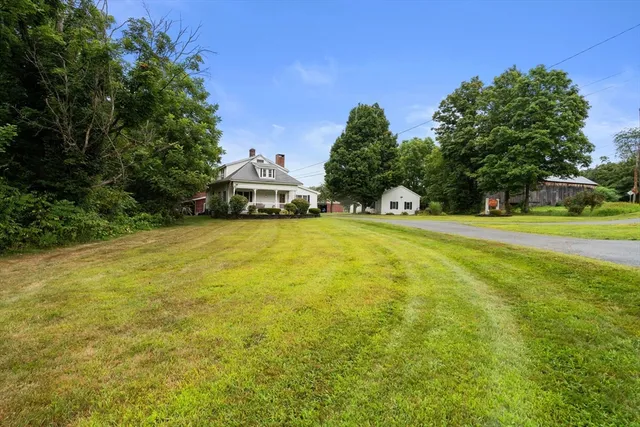 a view of a swimming pool with lawn chairs and large trees
