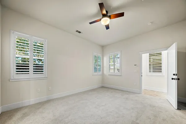 an empty room with windows and fan