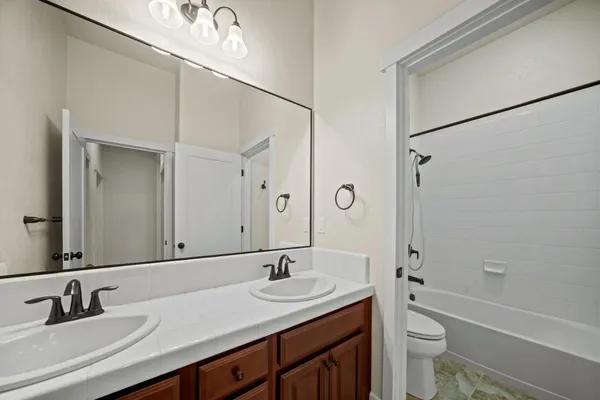 a bathroom with a double vanity sink toilet mirror and shower