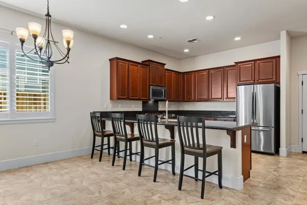 a kitchen with stainless steel appliances granite countertop a stove a refrigerator a microwave oven with a dining table and chairs