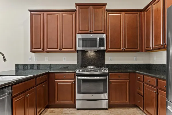 a kitchen with granite countertop wooden cabinets and a stove top oven