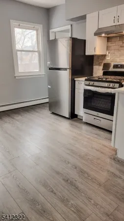 a kitchen with a refrigerator stove and wooden floor