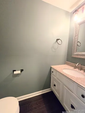 a bathroom with a granite countertop toilet and a sink