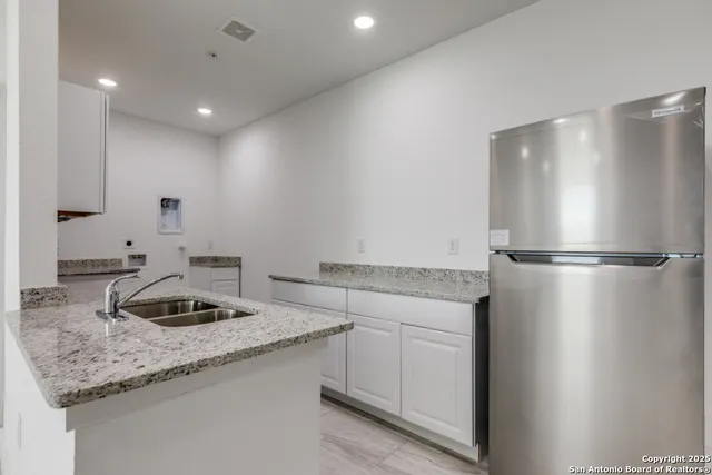 a kitchen with granite countertop stainless steel appliances a refrigerator and a sink