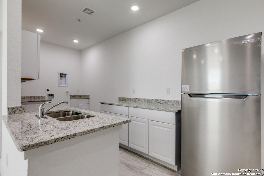 5415 Ingram Road, Unit 1203 San Antonio, TX 78228 - Photo 6 of 12 a kitchen with granite countertop stainless steel appliances a refrigerator and a sink