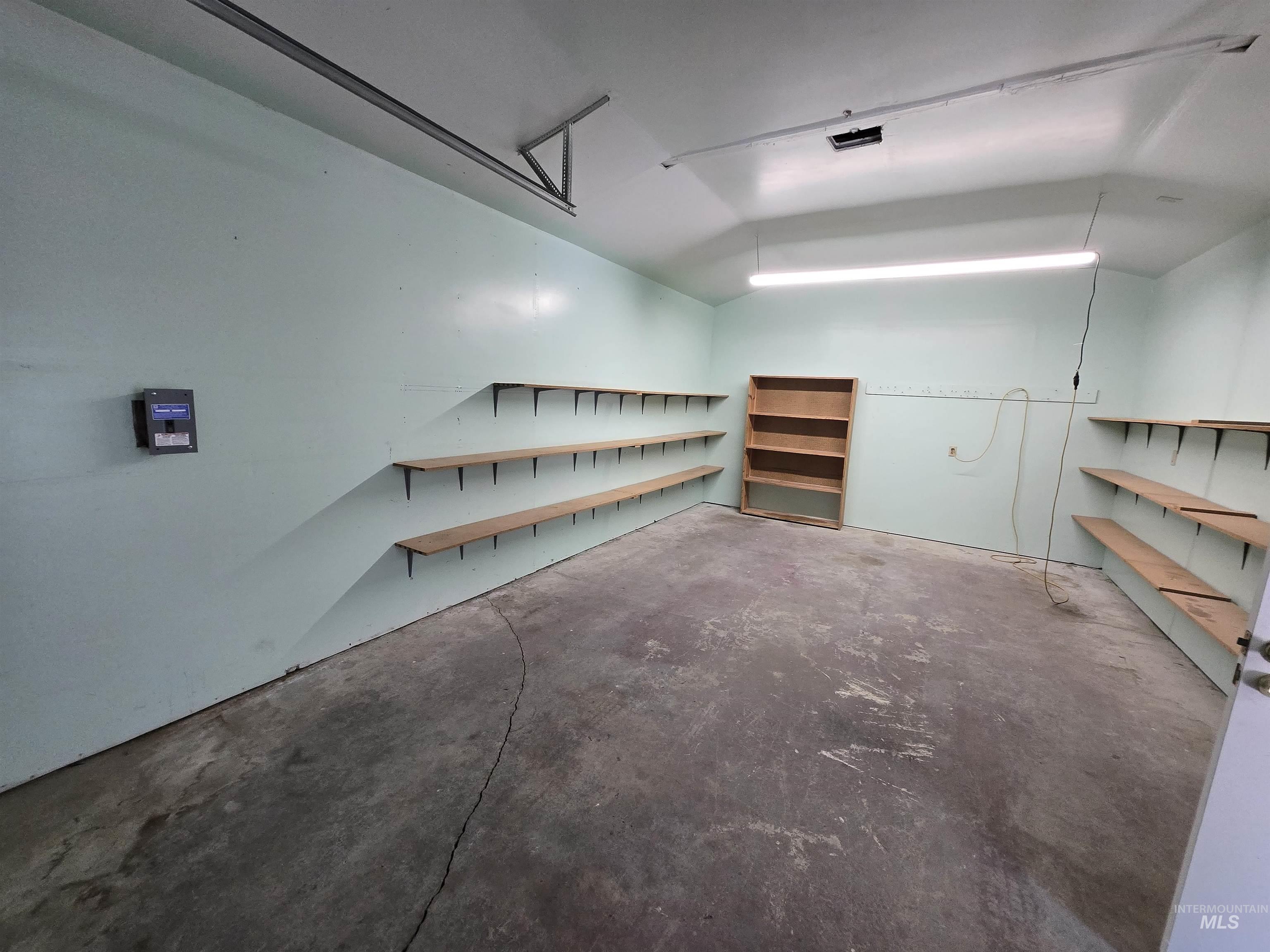 12050 West Hidden Valley Rim Road Boise, ID 83709 - Photo 27 of 39 Spacious garage featuring extensive built-in shelving, a freestanding wooden bookshelf, and exposed concrete flooring