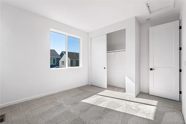 a view of an empty room with closet and windows