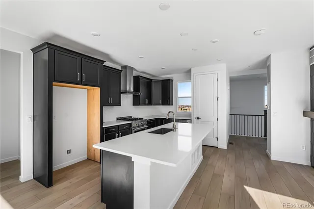 a kitchen with a refrigerator a sink and wooden floor