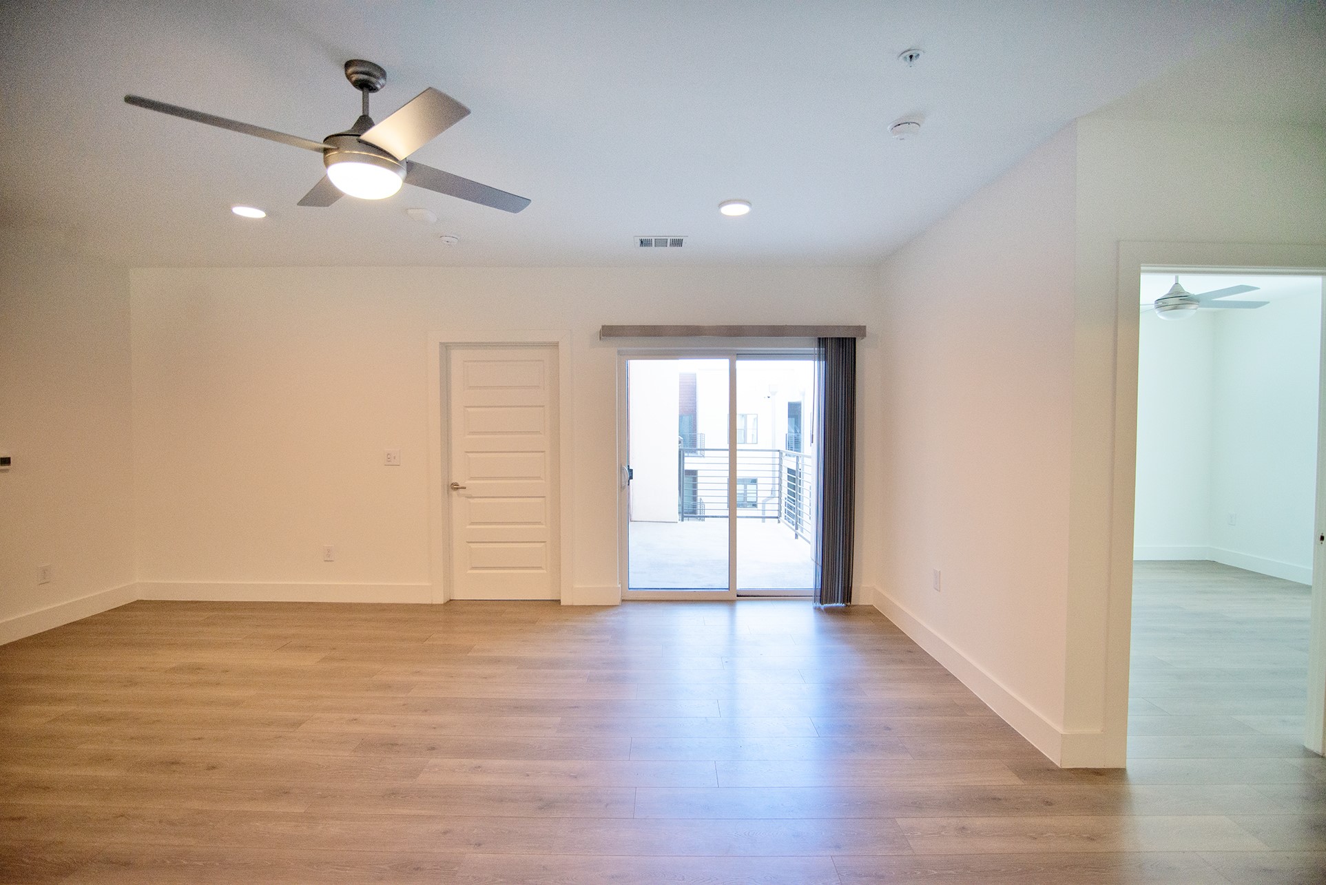 2213 Poquito Street, Unit 313 Austin, TX 78722 - Photo 10 of 26 a view of an empty room with wooden floor and a ceiling fan