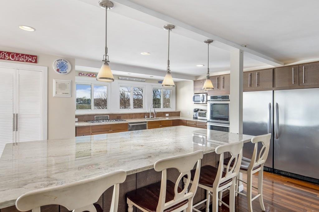 62 Surfside Road Scituate, MA 02066 - Photo 3 of 19 a kitchen with stainless steel appliances kitchen island granite countertop a table chairs and wooden floors