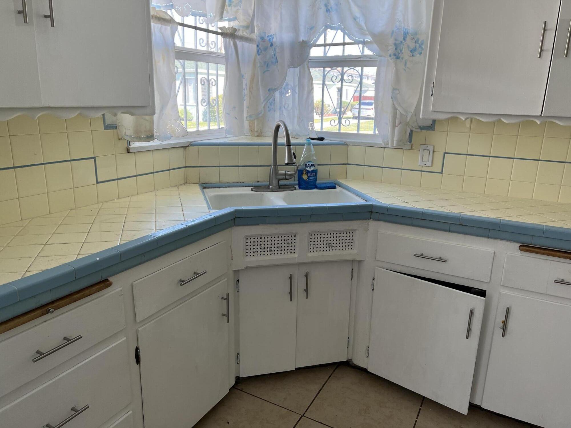 4916 Brompton Avenue Bell, CA 90201 - Photo 22 of 50 a kitchen with white cabinets and a sink