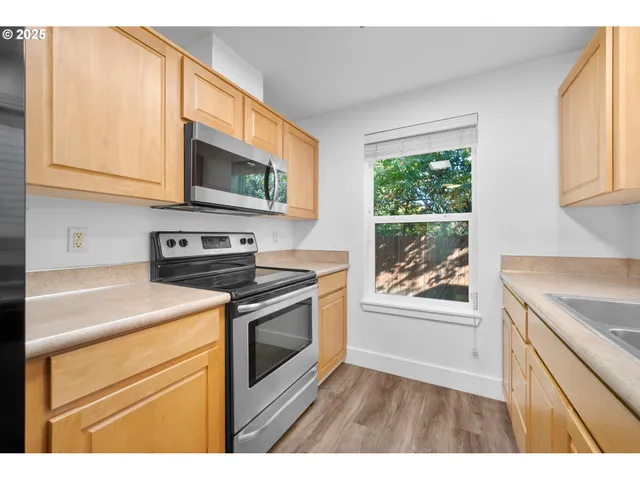 a kitchen with granite countertop a sink a window and cabinets