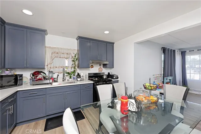a kitchen with stainless steel appliances a sink a stove a table and chairs