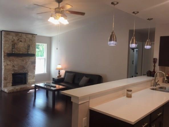 3305 Spaniel Drive Austin, TX 78759 - Photo 14 of 20 Stone-clad fireplace and rich hardwood floors anchor this inviting living area, flowing into a modern kitchen.