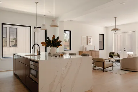 a kitchen with stainless steel appliances kitchen island granite countertop a dining table chairs and a refrigerator