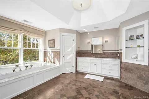 a large bathroom with a tub sink and mirror