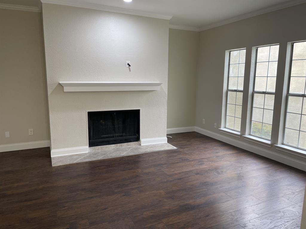 5310 Keller Springs Road, Unit 423 Dallas, TX 75248 - Photo 2 of 7 Unfurnished living room with crown molding, dark wood-style flooring, and a fireplace with flush hearth