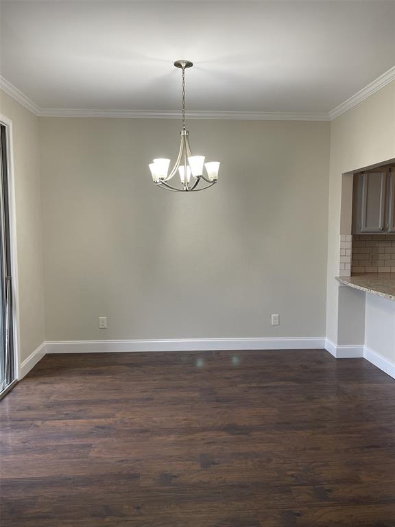 5310 Keller Springs Road, Unit 423 Dallas, TX 75248 - Photo 6 of 7 Unfurnished dining area with ornamental molding, dark wood-style flooring, and suspended lighting