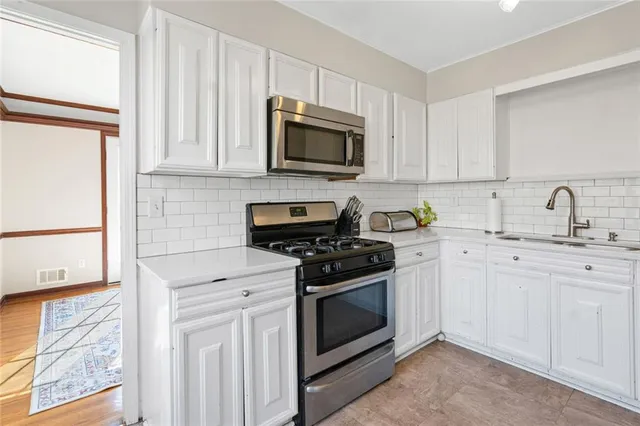 a kitchen with stainless steel appliances granite countertop white cabinets a stove top oven and sink