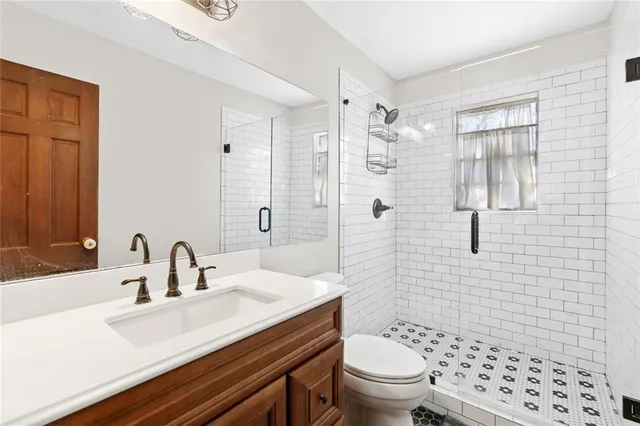 a bathroom with a sink a toilet a shower and a mirror