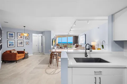 a kitchen with stainless steel appliances a sink a stove a dining table and chairs