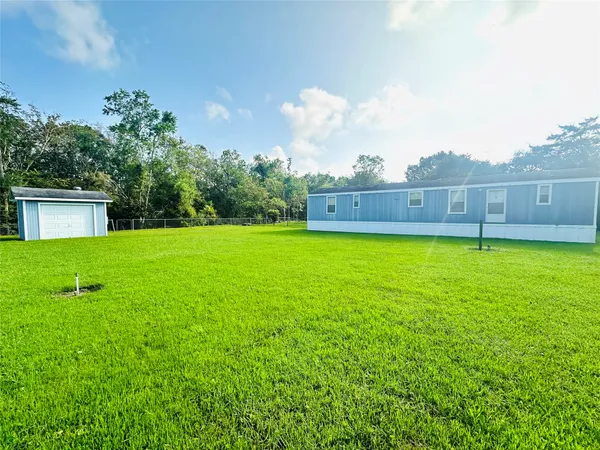 a view of a house with a yard and a large tree