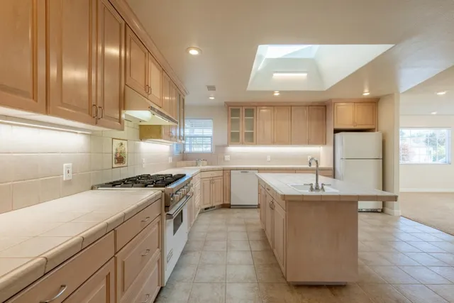 a kitchen with stainless steel appliances granite countertop a sink a stove and a refrigerator