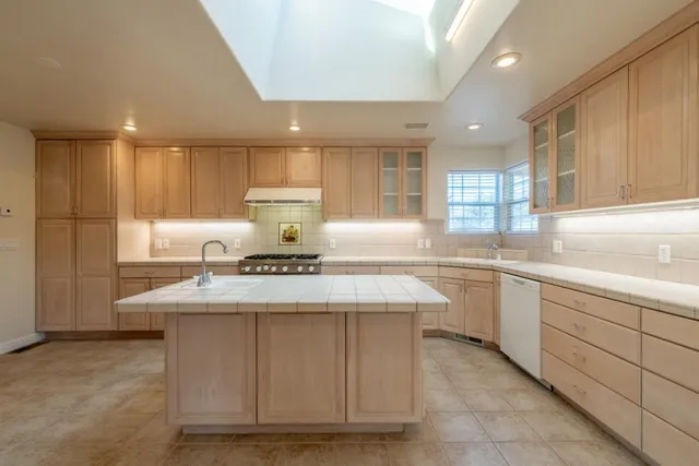 a kitchen with kitchen island granite countertop wooden cabinets and white stainless steel appliances