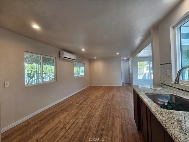 a kitchen with granite countertop a sink a stove wooden floor and cabinets