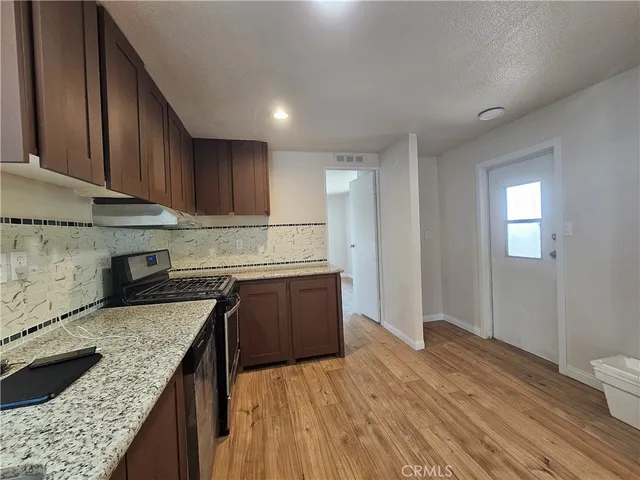 a kitchen with granite countertop wooden cabinets a sink and dishwasher