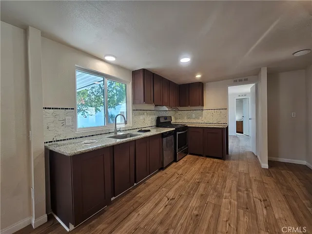a kitchen with stainless steel appliances granite countertop wooden cabinets a window a sink and a counter space