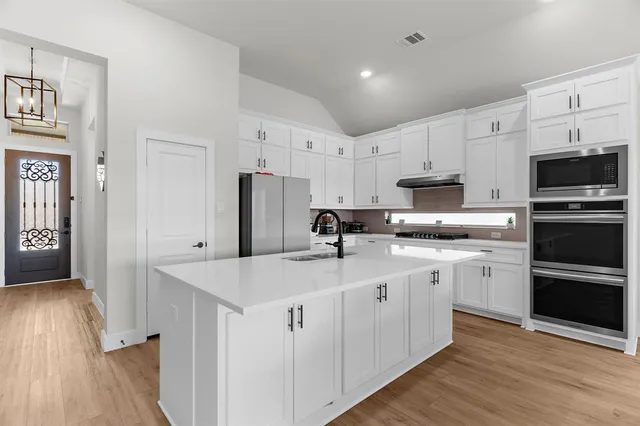 a kitchen with stainless steel appliances granite countertop a refrigerator sink and white cabinets
