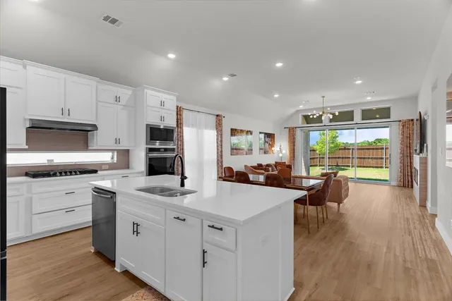 a kitchen with a stove a sink a microwave a dining table and chairs