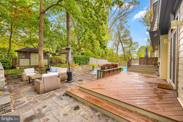 a view of a patio with couches and table and chairs with wooden floor and fence