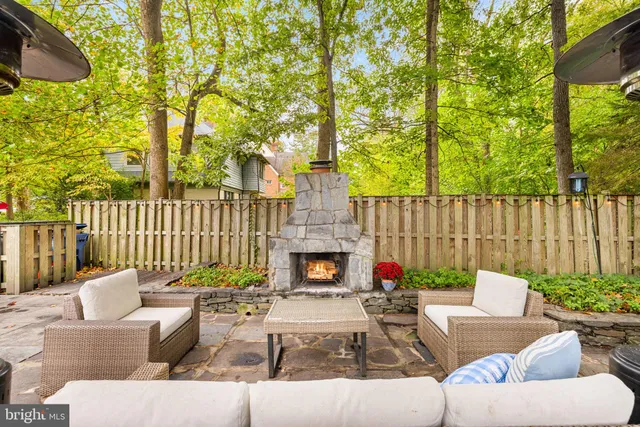 a view of a patio with couches chairs and a fire pit with wooden fence