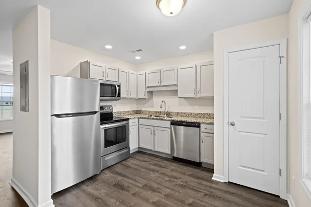a kitchen with cabinets stainless steel appliances and wooden floor