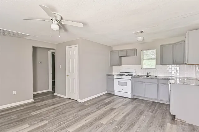 a kitchen with granite countertop a stove top oven sink and cabinets