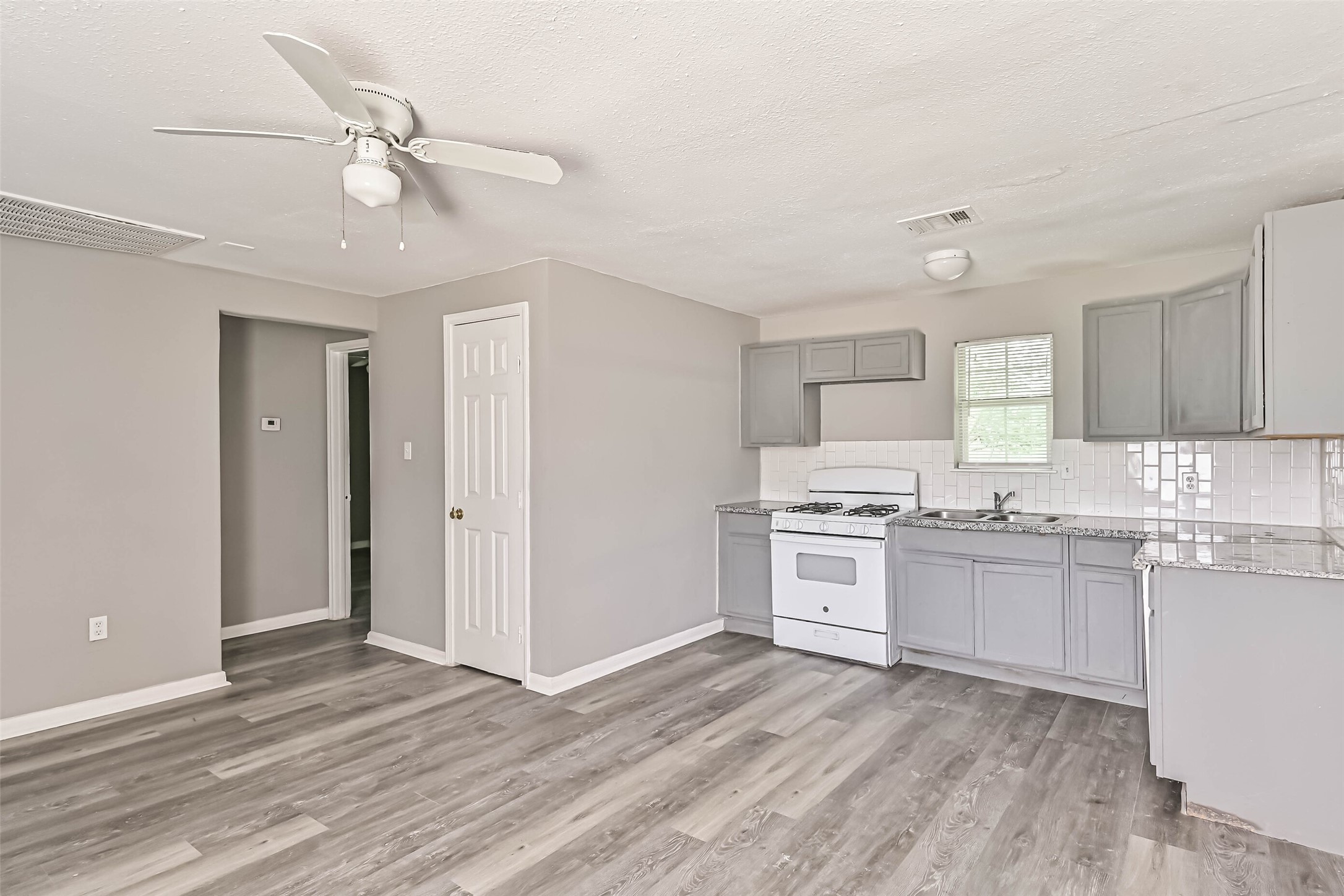 9839 Racine Street, Unit 1/2 Houston, TX 77029 - Photo 11 of 26 a kitchen with granite countertop a stove top oven sink and cabinets